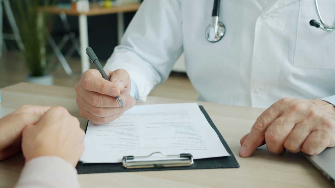 A physician reviewing a patient’s medical history form during a consultation.