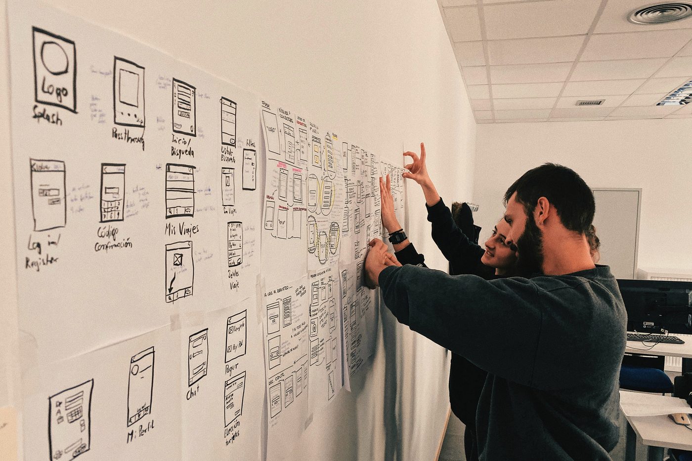 Two colleagues planning a build together on a wall of sketches, the kind of hands-on design Workstream as a Service keeps running.
